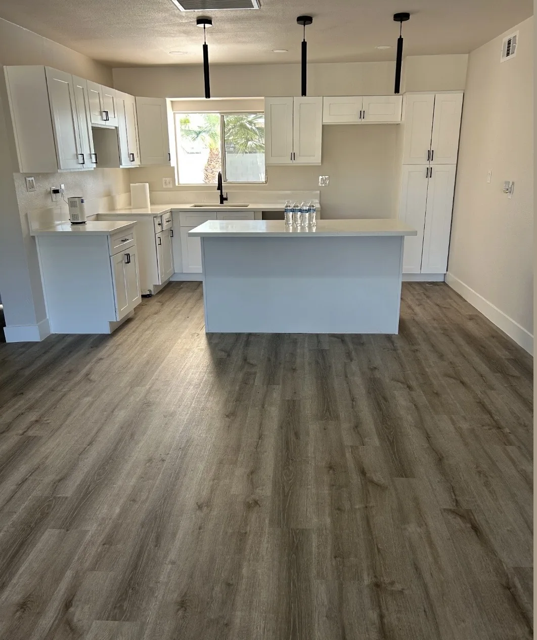 Kitchen with white cabinets, an island, and wood-look flooring
