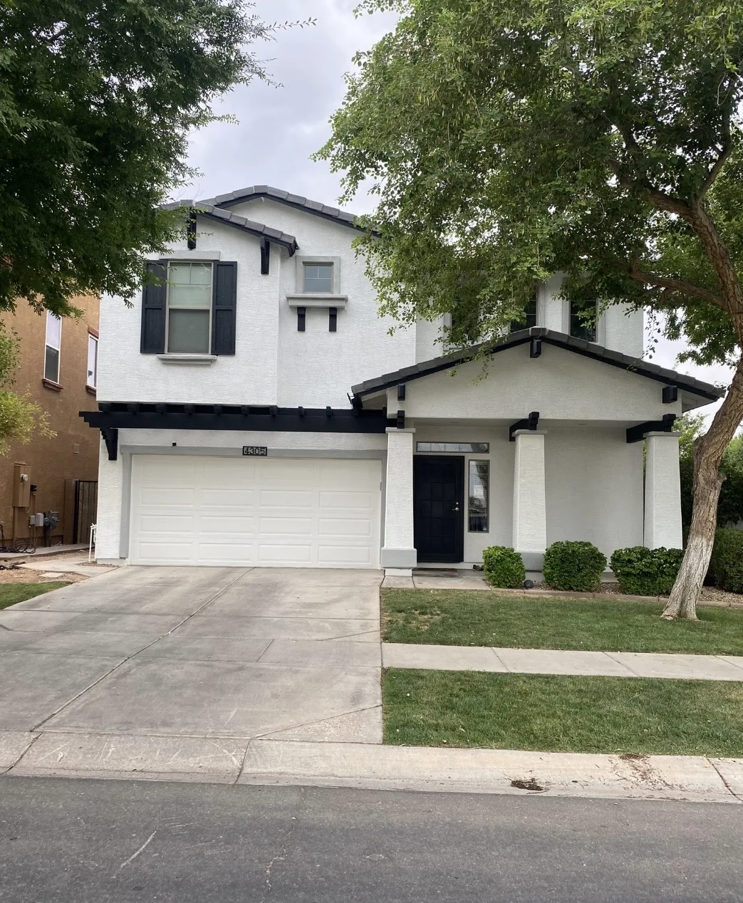 White two-story home with dark trim and a front porch
